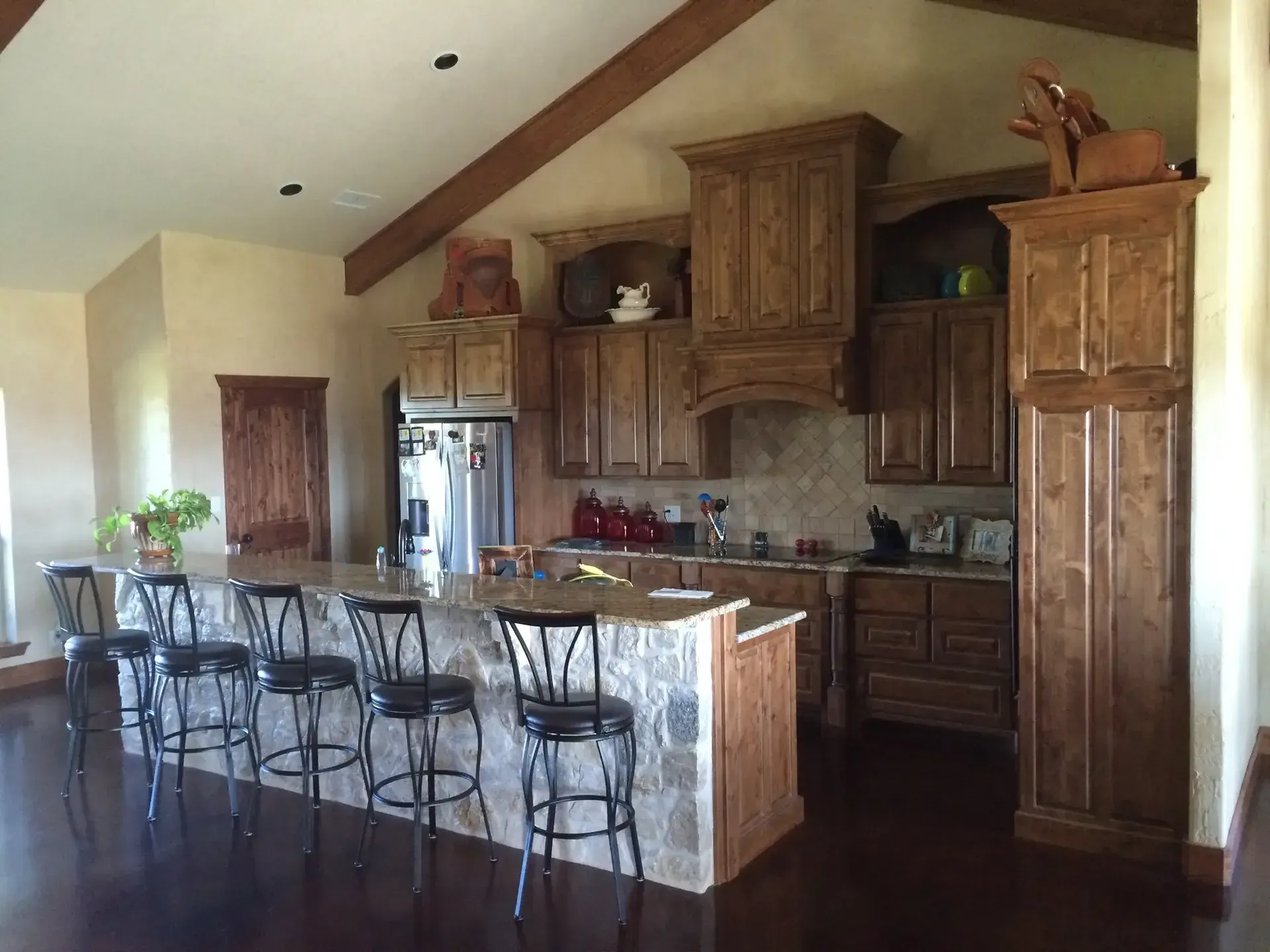 view of a older style kitchen with brown cabinets and espresso colored flooring.