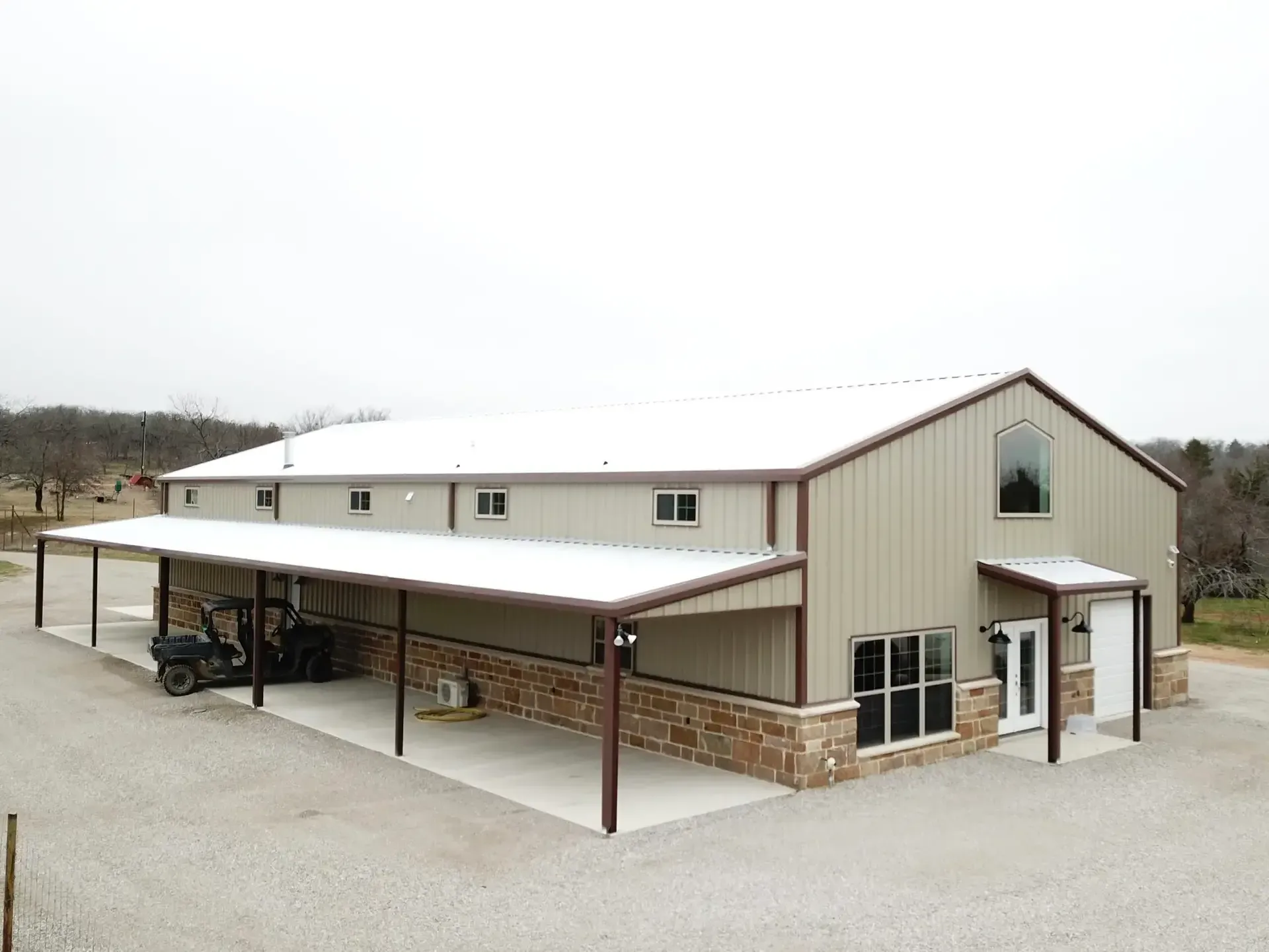 tan barndominium with white roof and brown gutters