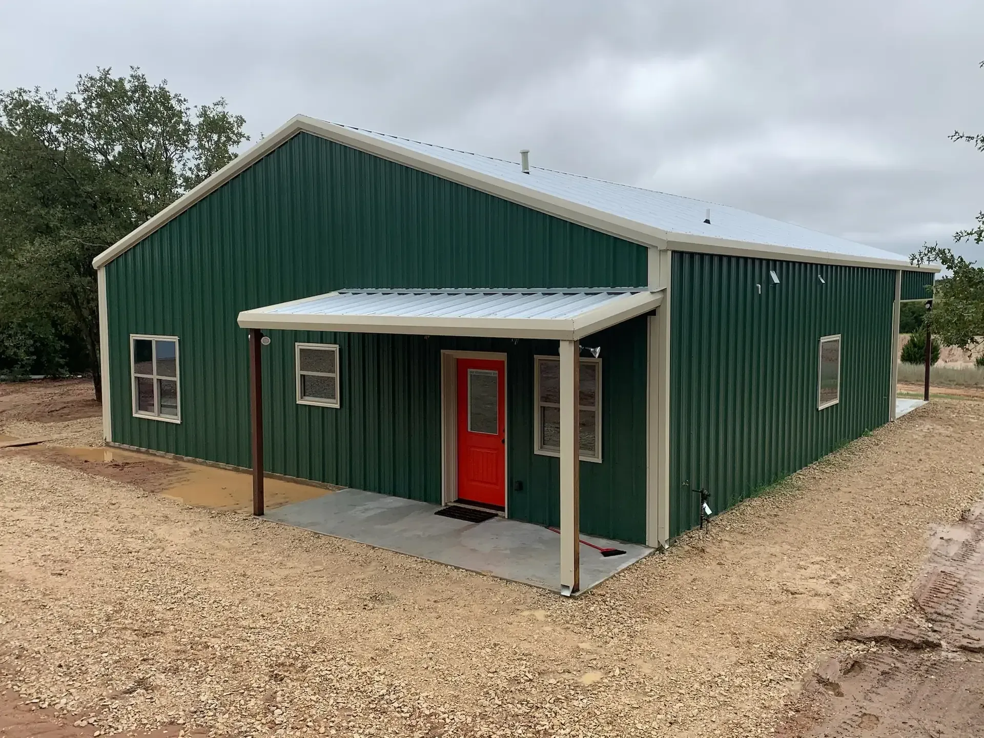 Green barndominium with bright red door