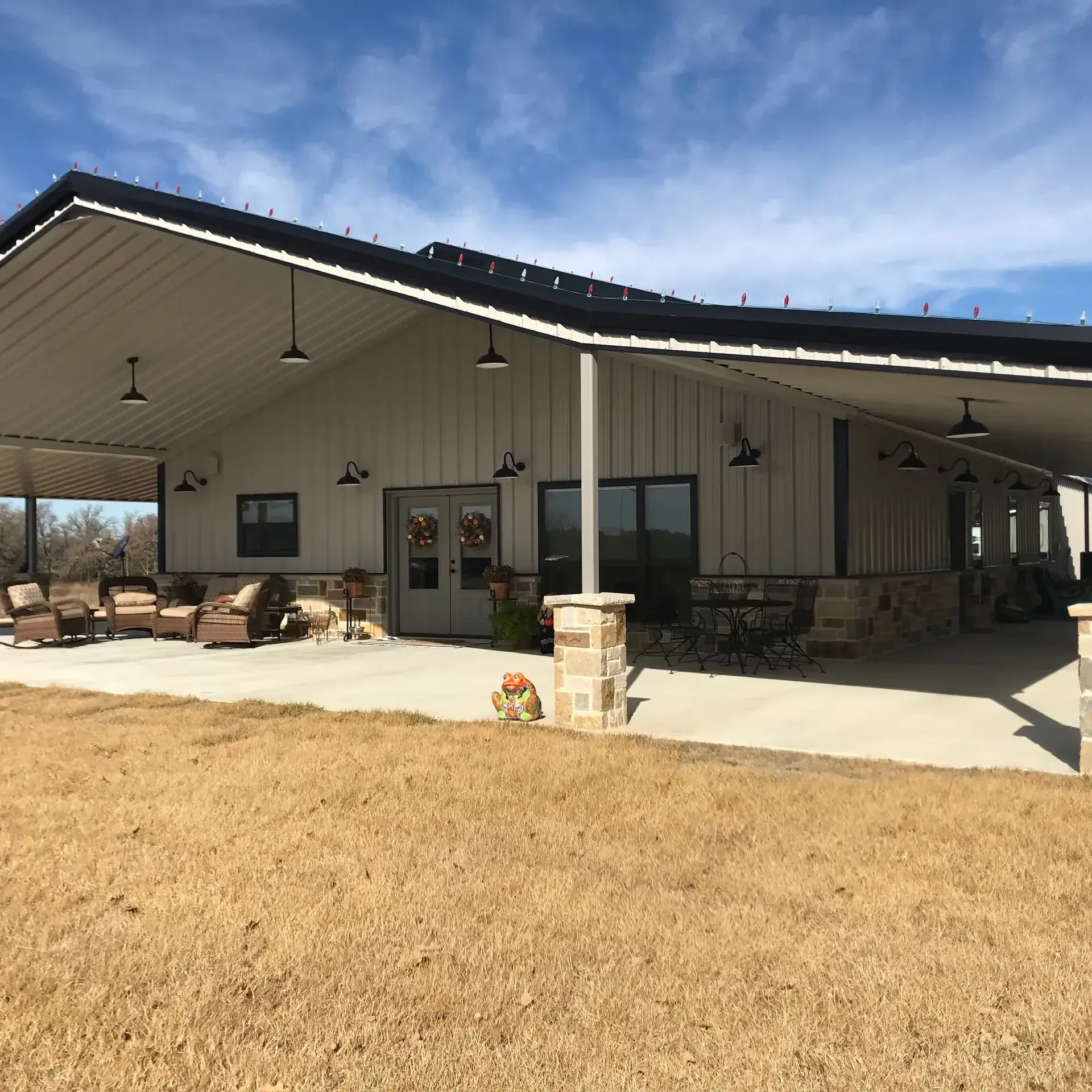 tan and charcoal barndominium with huge porch and decrative stone siding