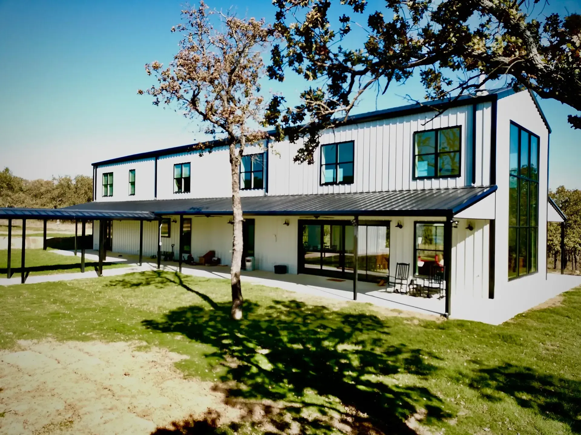 Black and white two story modern barndominium with a porch